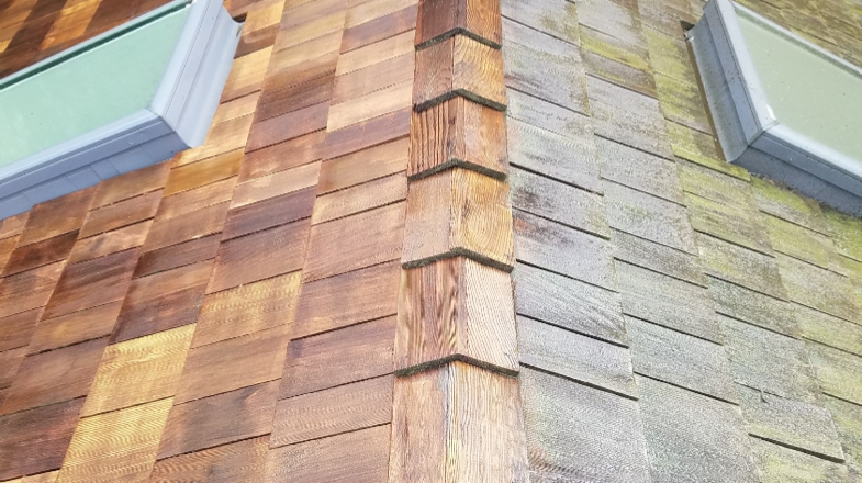 Cedar shake roof with one slope freshly washed and the other still gray with moss